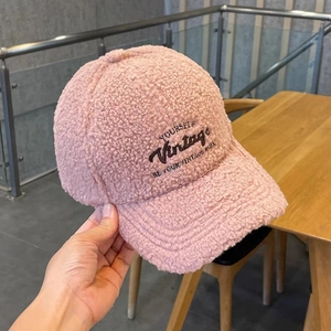 Dettaglio della texture in lana d'agnello rosa e ricamo vintage nero sul cappellino