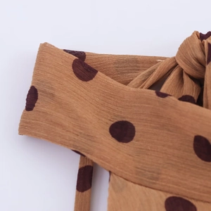 Detailopname van de bruine polka dot chiffon stoftextuur van een midi-jurk