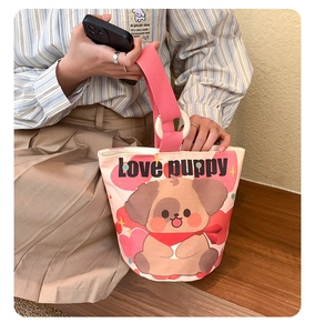 Detail of canvas tote bag with brown cartoon puppy print and pink woven handles