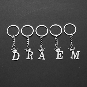 Set of silver stainless steel crown letter keychains spelling DREAM on a dark surface