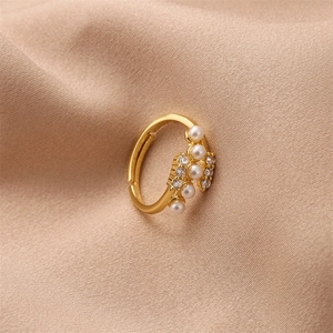 Close-up of gold open ring with white pearls and sparkling zircons on silk background