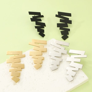 Detailed view of geometric step earrings in matte black, mirrored gold, and silver finishes