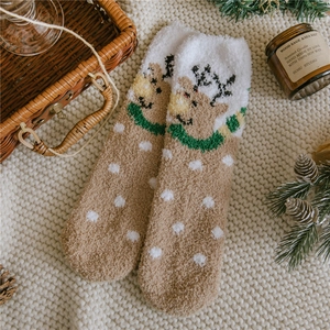 Close-up of warm coral fleece Christmas elk socks with festive pine cones and decor