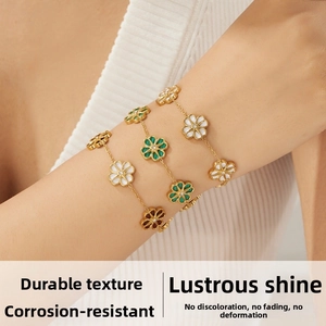 Close-up of gold chain bracelets with daisy pendants in white, green, and brown stones