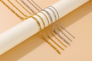 Close-up of gold and silver titanium steel Figaro and curb chains on white stands