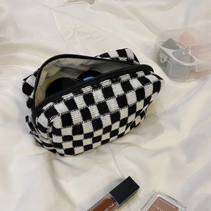 Top view of a thick knit checkered cosmetic bag filled with makeup accessories