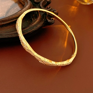 Detail of gold plated wave bangle with pavé cubic zirconia on vintage brown leather