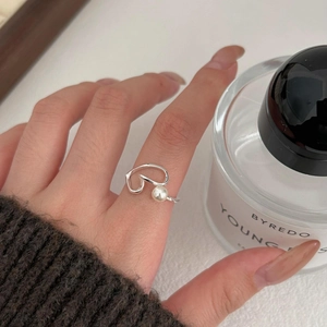 Detail of S925 silver heart ring with pearl inlay worn by a model in a cozy setting