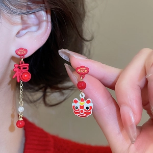 Detailed view of asymmetric Chinese lion earrings with red lacquer, pearls and Rich lettering