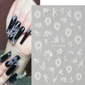 Detail view of Halloween nail art stickers with white spider web and heart patterns