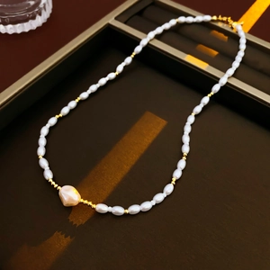Close-up of pearl and gold beaded necklace with a large irregular pearl on display