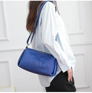Bolso toast de nailon azul con correa ajustable mostrado de perfil en un modelo