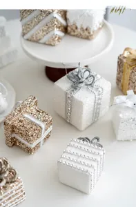 Close-up of champagne gold and white glitter Christmas gift box ornaments with pearl details