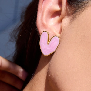 Boucles d'oreilles cœur rose avec bord doré, portées par un mannequin sous lumière naturelle