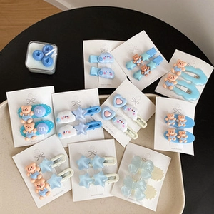 Macro detail of various plastic hair clips featuring bear, star, and heart designs on cards