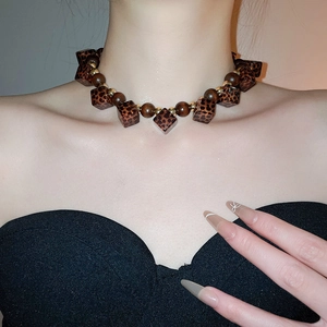 Detail of beaded necklace with leopard print acrylic squares and wooden beads on model neck