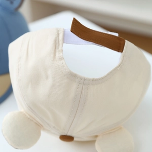 Close-up of baby baseball cap with brown adjustable strap and cute plush ears detail