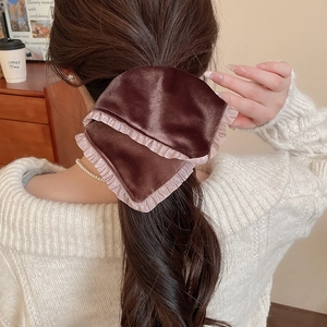 Detail of dark brown velvet bow hair clip with pink pleated lace edges on a ponytail