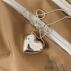 Detailed view of a silver heart-shaped pendant with polished finish on a beaded chain
