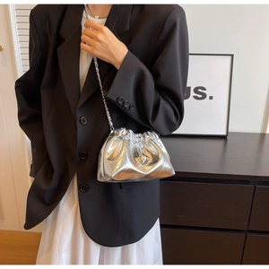 Detail view of a silver metallic drawstring bucket bag with chain strap and pearl accents