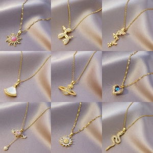 Collection of nine gold necklaces with zircon pendants on purple satin background
