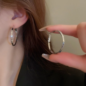 Close-up of a silver geometric hoop earring with sparkling crystal accents on model