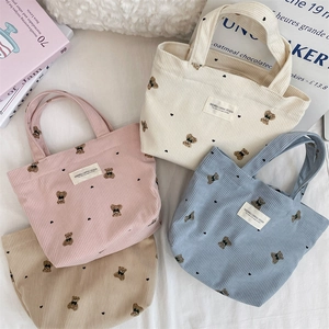 Flat lay of corduroy bear tote bags in pink, white, blue, and brown colors