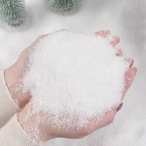 Artificial white snow powder for Christmas winter scene decoration in hand close-up