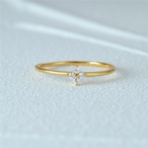 Macro shot of 18K gold ring with four round zircon stones in a floral cross pattern