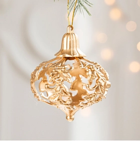 Detailed view of a golden hollow Christmas tree ornament hanging on a pine branch
