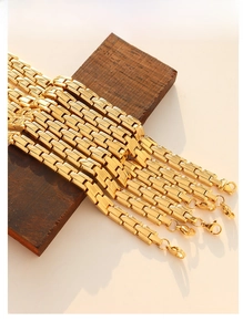 Detailed view of golden watch strap chain bracelets with polished finish on wooden stand