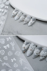 Macro detail of white 5D embossed rose and bow nail art stickers on matte grey nails