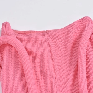 Détail macro de la texture du tissu seersucker rose vif sur ce pantalon tendance