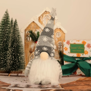 Close-up of grey plush Christmas gnome with snowflake hat against festive background