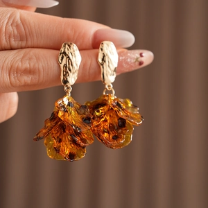 Macro shot of gold textured metal studs with amber resin petal-shaped pendants