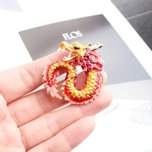 Detailed close-up of a golden Chinese dragon brooch with red and yellow enamel craft