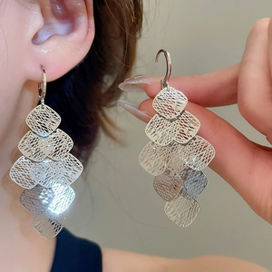 Detail of layered geometric hollow diamond tassel earrings with elegant metallic texture