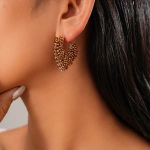 Close-up of vintage bronze beaded heart earrings worn by a model in a stylish detail view