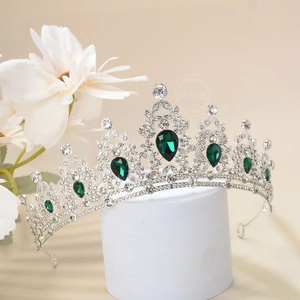 Detail of luxury crown with emerald green teardrop gems and white rhinestones