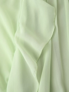 Detailed macro view of light green chiffon fabric texture with ruffle pleated edges
