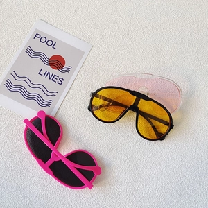 Detail view of vintage sports kids sunglasses in yellow and pink colors on white texture