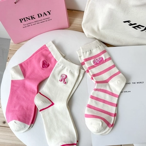 Detail showing pink and white striped cotton socks with cute bear embroidery on a plate