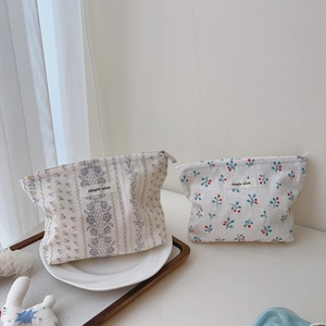 Detail of floral cotton makeup bags with zippers and simple wish label on ceramic tray