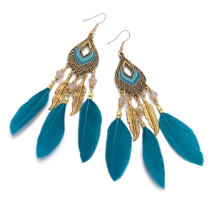 Detailed view of bohemian teardrop earrings featuring peacock blue feathers and gold charms