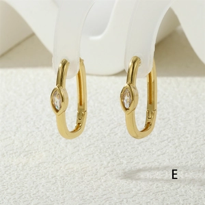Macro detail of gold U-shaped hoop earrings with marquise-cut crystal on frosted stand