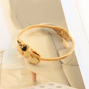 Detail of gold butterfly bangle featuring matte and black enamel textures with spring clasp