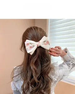 Detailed embroidery on white lace bow hair clip featuring delicate floral patterns