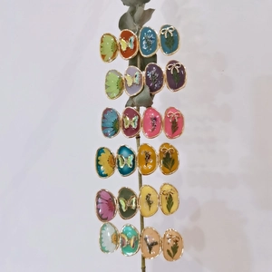 Detailed macro view of resin hair clips with dried flowers and butterfly motifs in gold
