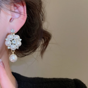 Detailed close-up of golden floral earrings with white pearls and sparkling rhinestones