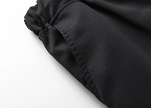 Detailed close-up of side pockets and fine stitching on black cargo shorts fabric